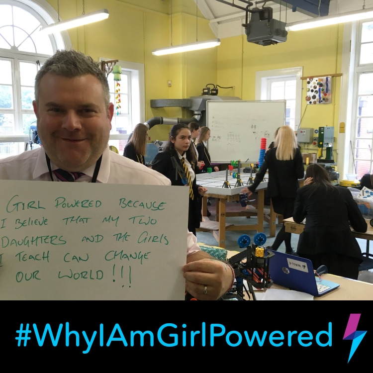 Robotics coach holds a sign that says,