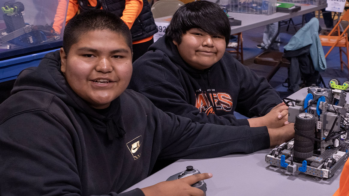 Team sit at table with robot at Native American Showcase