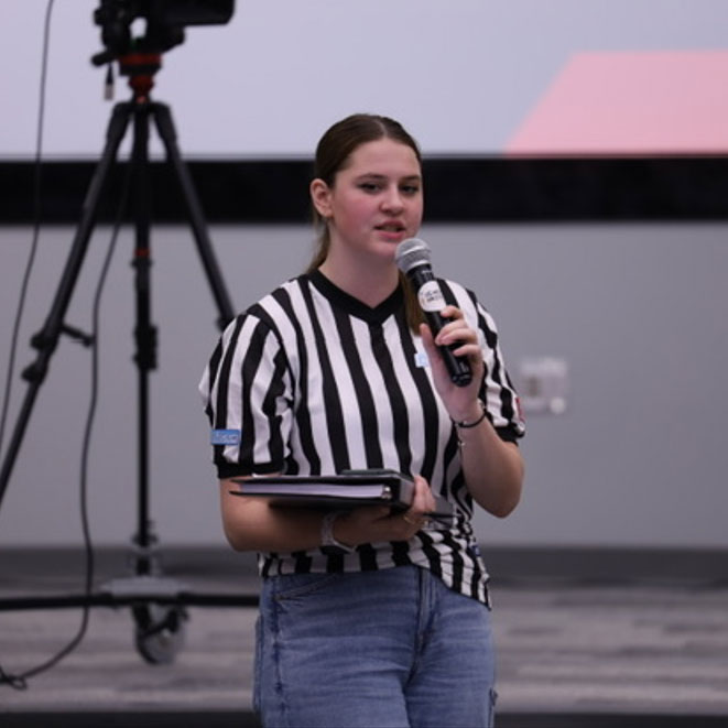 Volunteer McKenzie Koch speaks into a microphone during a robotics event