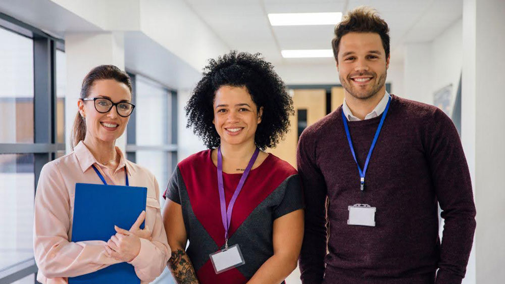 The educators pose in a hallway